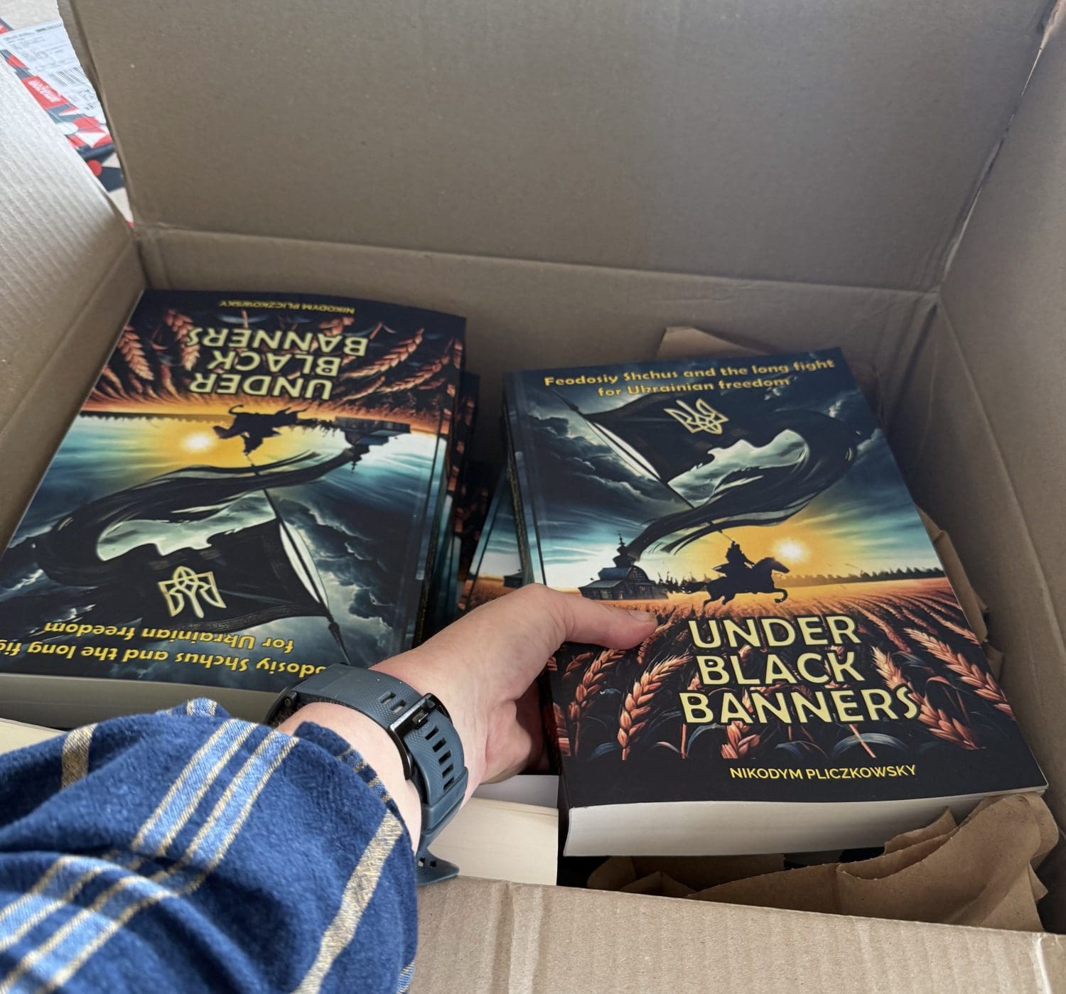 a hand reaching into a box of books under black banners