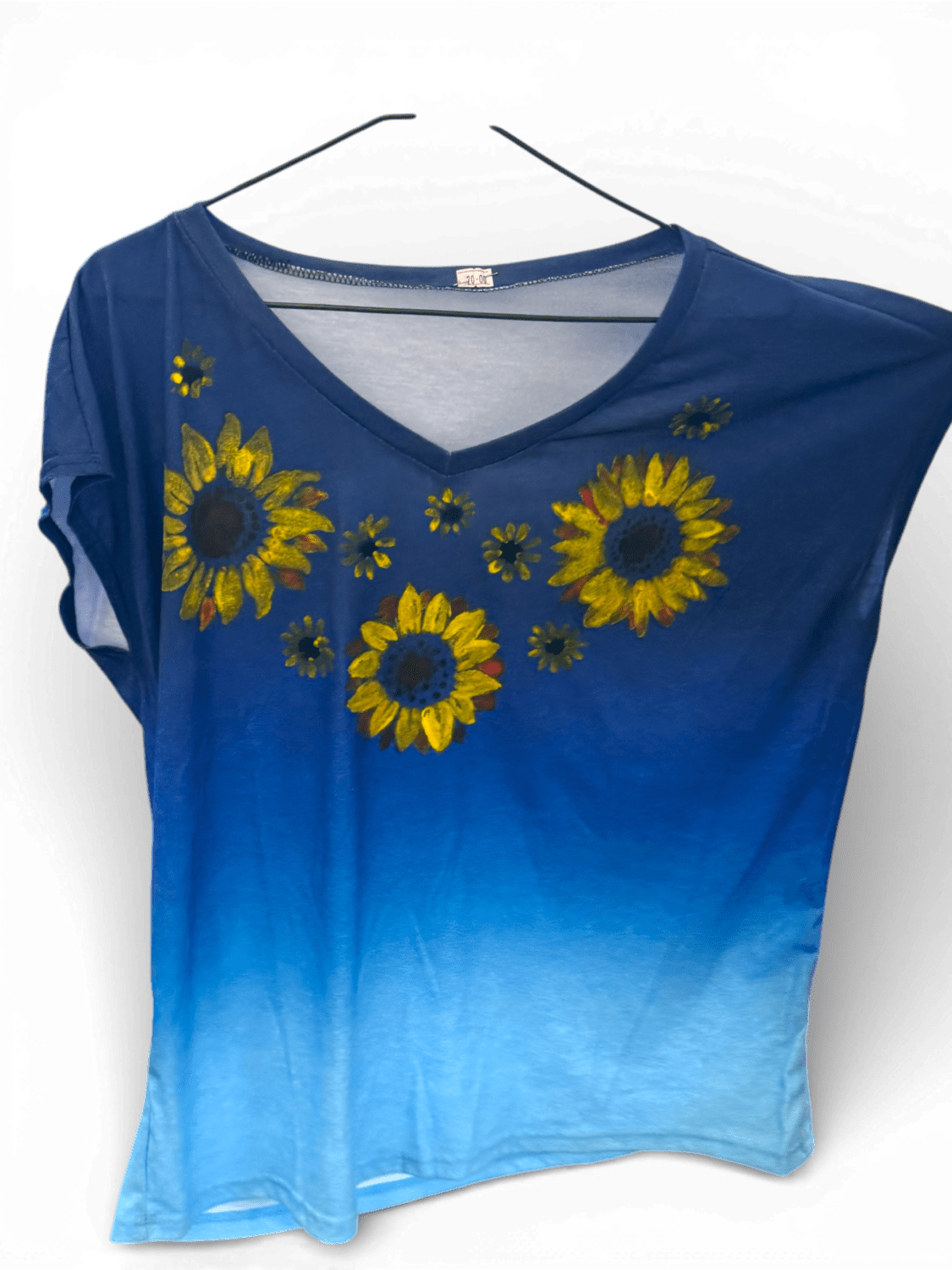 Blue gradient V-neck T-shirt with yellow sunflower embroidery on the front, hanging on a hanger.