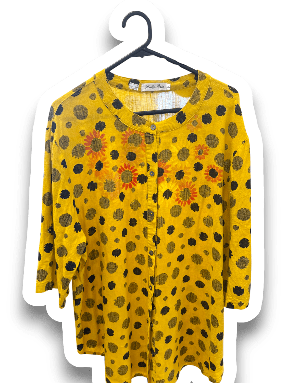 IMG_8029 Yellow long-sleeve blouse with black polka dots and orange sunflower prints on a hanger, front view showing collar and button placket.