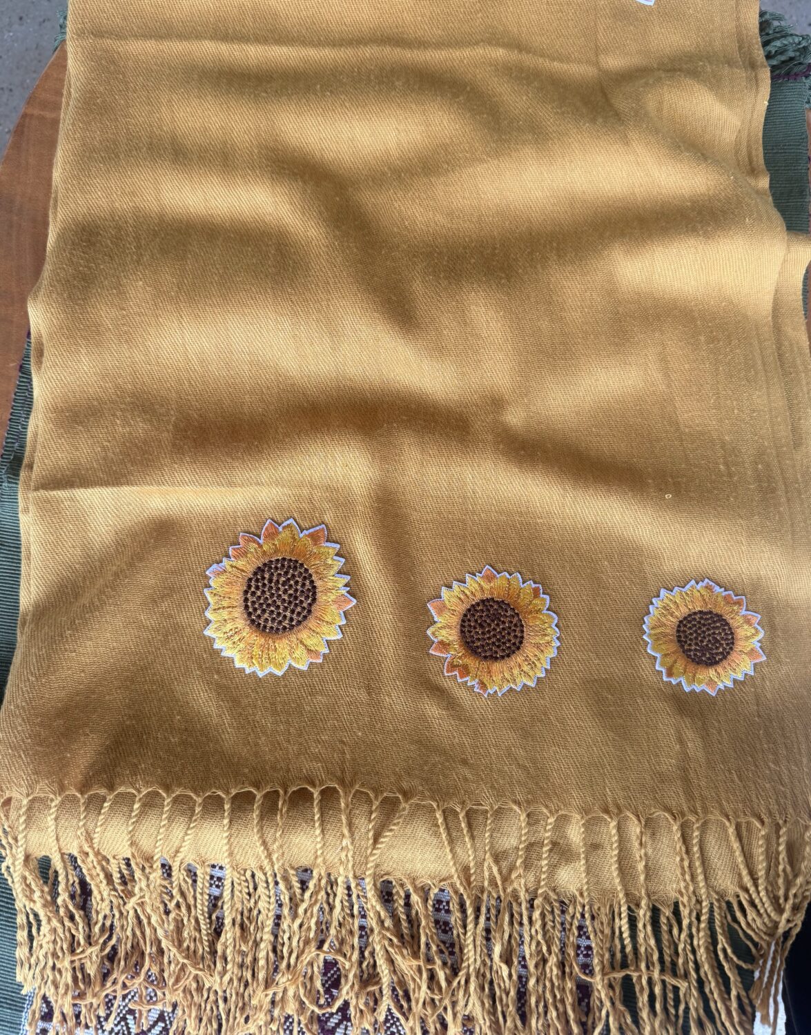 sunflower scarf Mustard-yellow scarf with three embroidered sunflowers near the bottom edge and a fringed hem.