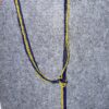 IMG_9159 Blue and yellow beaded necklace draped in a U-shape with a knot and hanging strands on a gray fabric background.